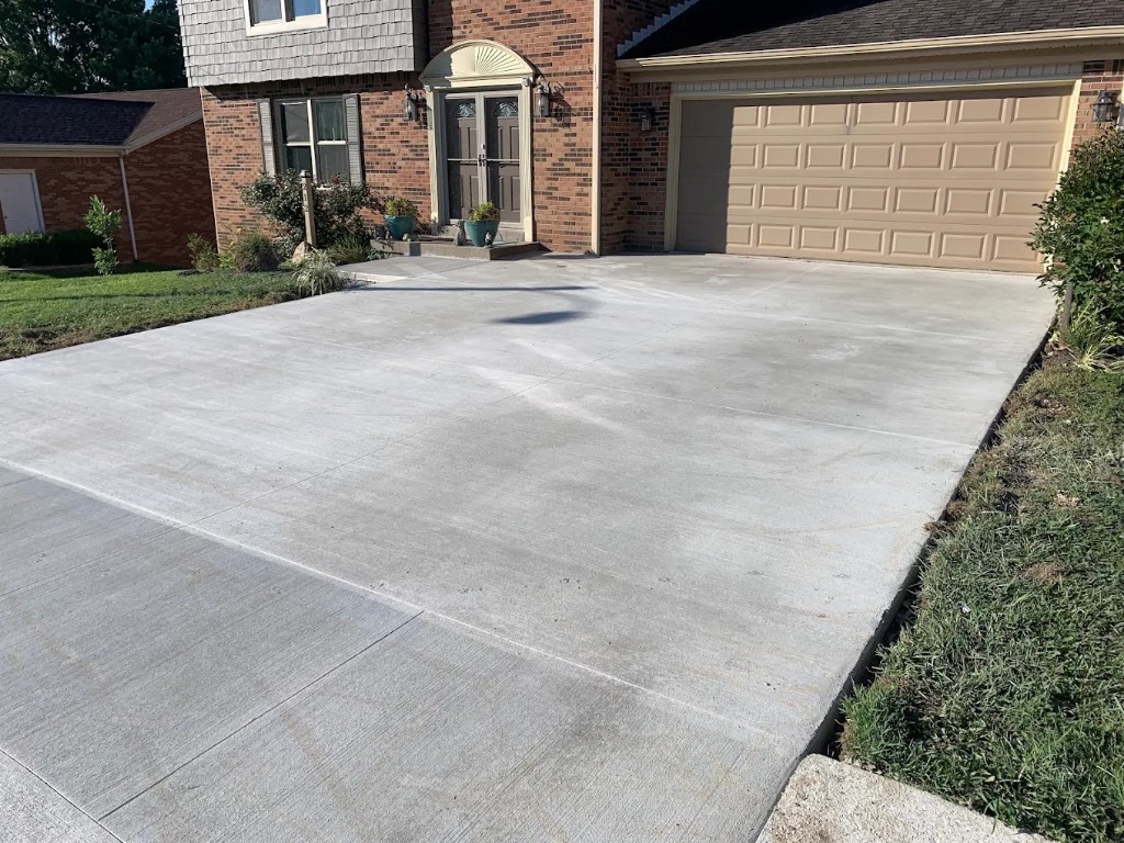 Broom-finished concrete driveway at a brick house