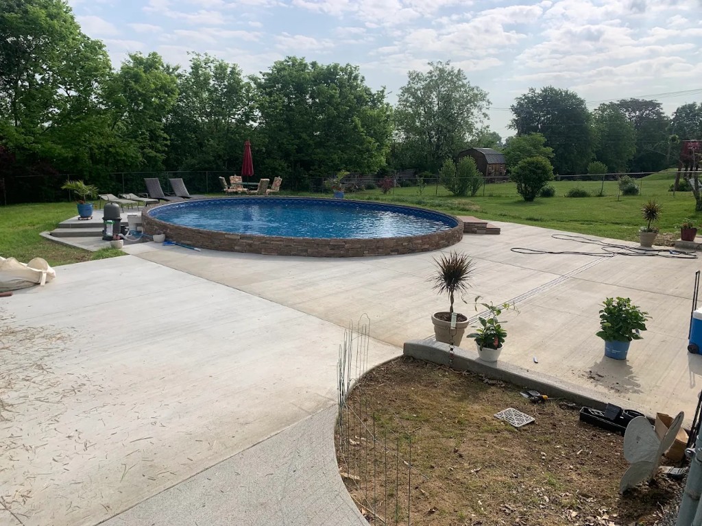 Wide concrete patio surrounding an above-ground pool