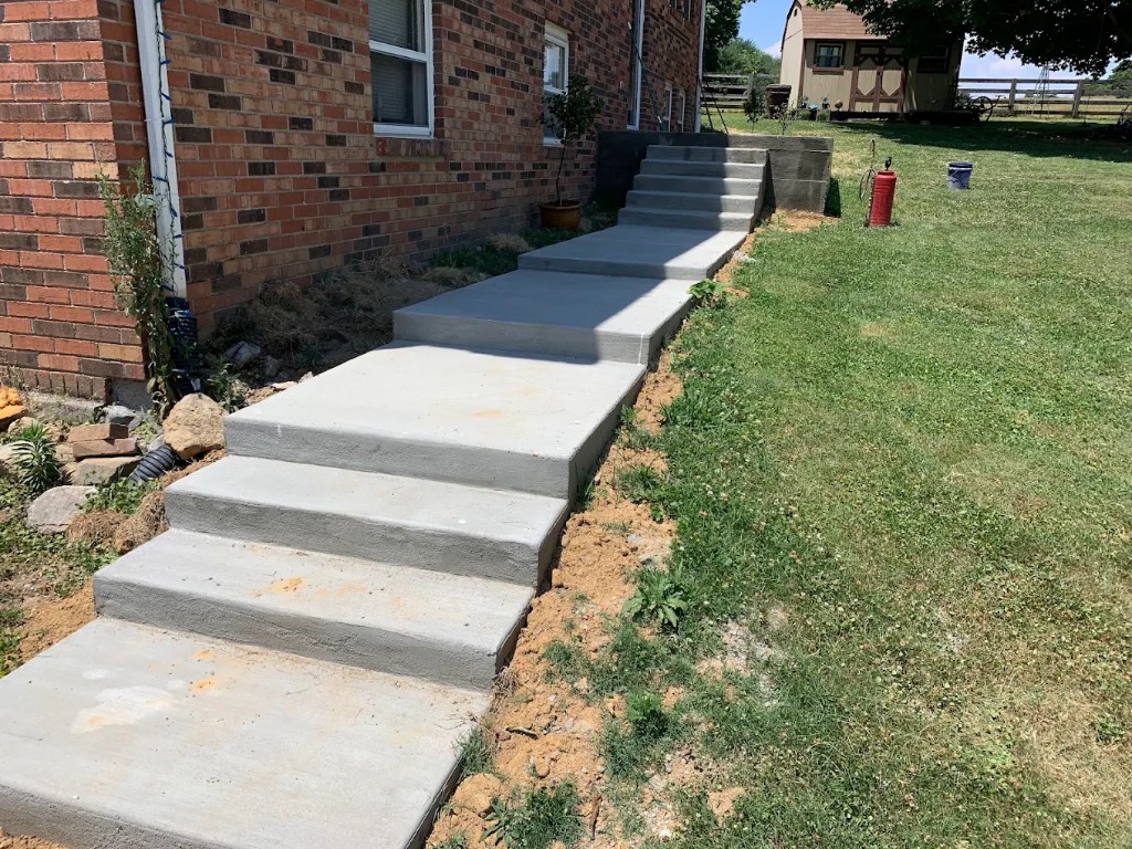 Concrete steps and landings along the side of a brick house