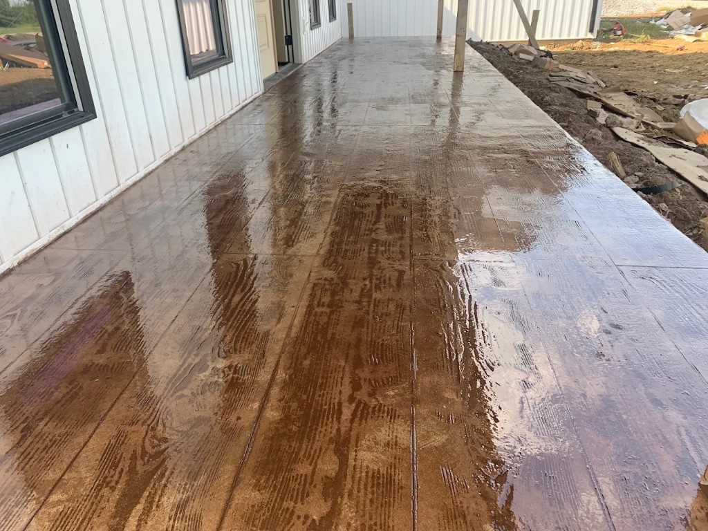 Wood-grain stamped concrete porch along a white metal-sided home