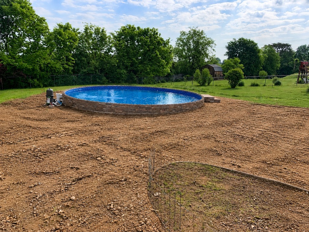 Before: above-ground pool sitting in an open dirt yard before the patio was poured